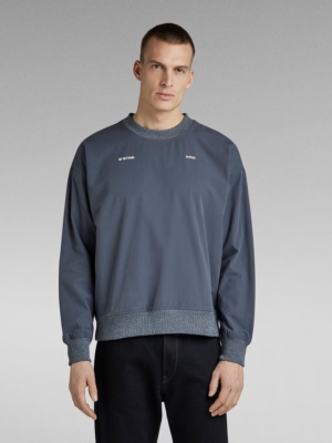 Le sweat Woven présente une coupe ample et des poches à passepoil simple sur le devant. Les manches et la taille de ce sweat doublé sont terminées par un bord côtelé pour plus de confort. Les motifs imprimés sur la poitrine viennent signer ce modèle.